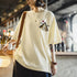 Person wearing a light yellow t-shirt with a graphic design in an indoor setting.